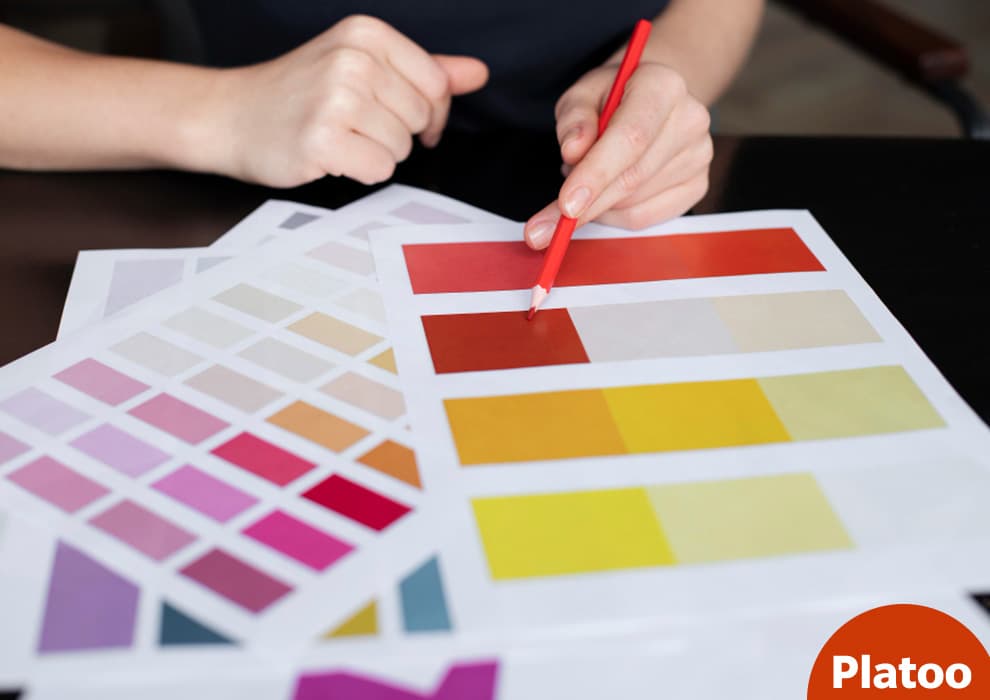A person choosing menu colors, marking printed color swatch sheets with a red pencil