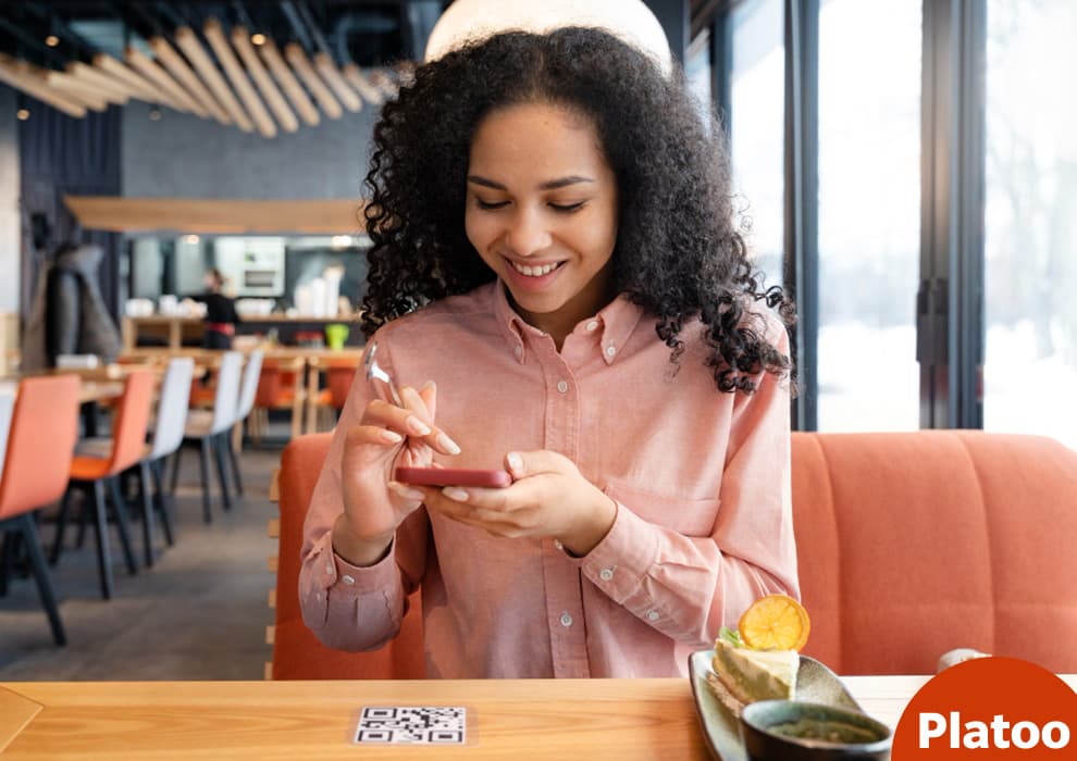 Client care scanează cu telefonul codul QR al meniului de pe o masă de restaurant