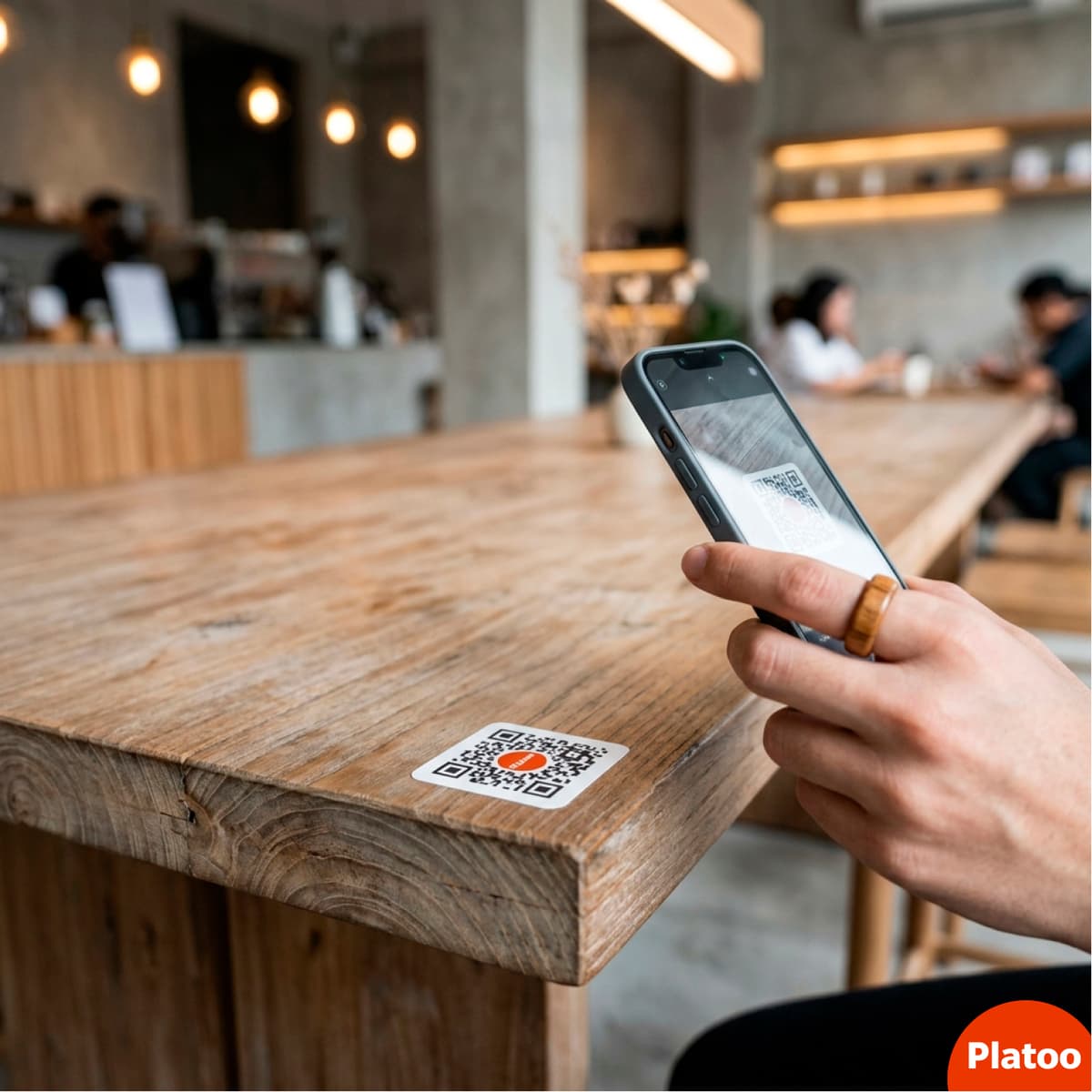 A matte vinyl sticker with a Platoo QR code placed on the edge of a wooden bar counter.
